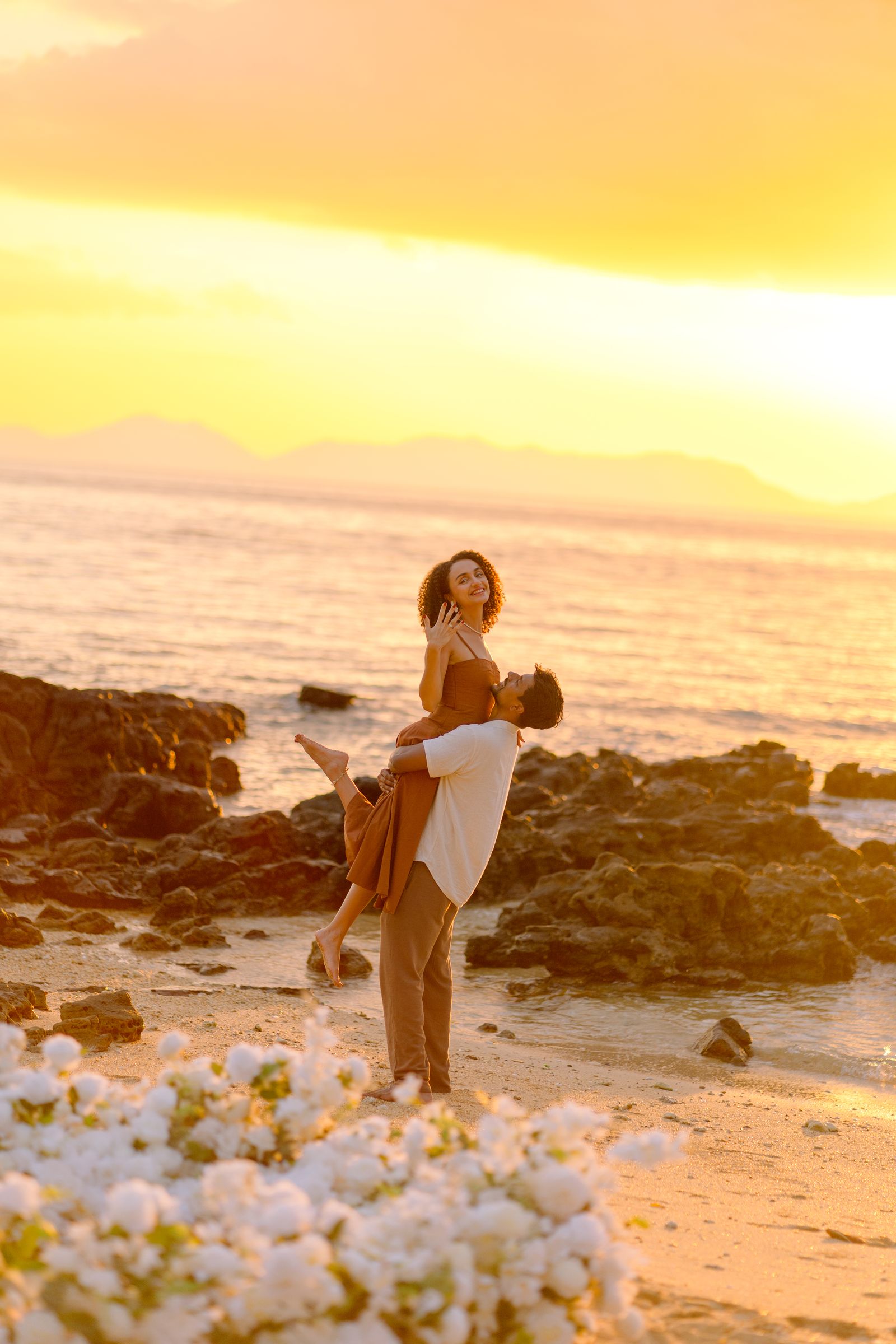 Nihal lifting Larissa on the beach